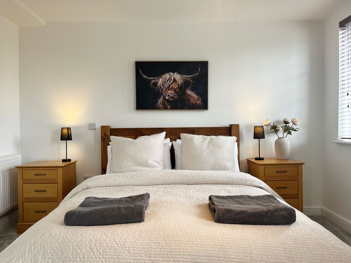 Main bedroom with a wooden bedstead, white linen, bedside lamps and fresh towels