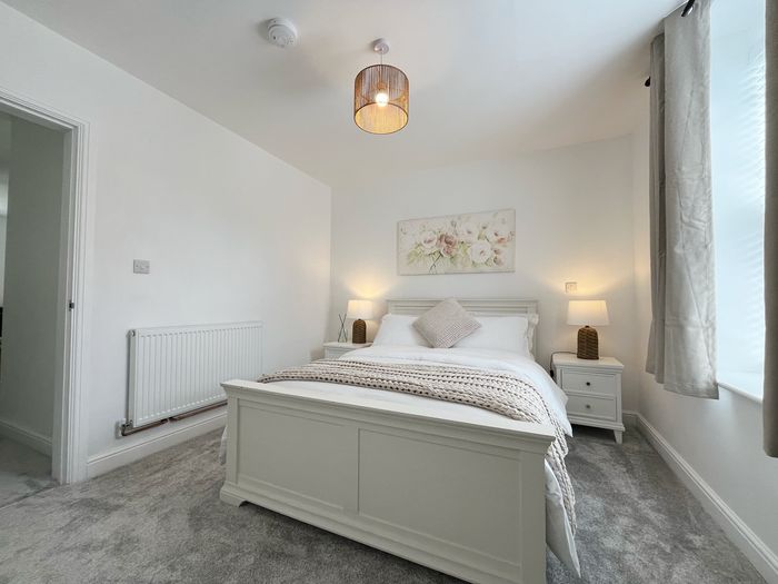 Bedroom seen from the doorway, with a full length mirror and curtained window