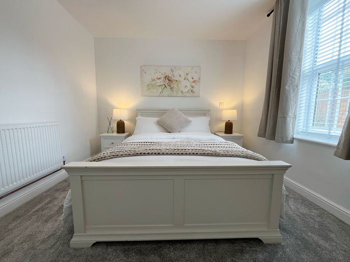 Bedroom with a painted wooden bedstead, crisp white linen and bedside lamps