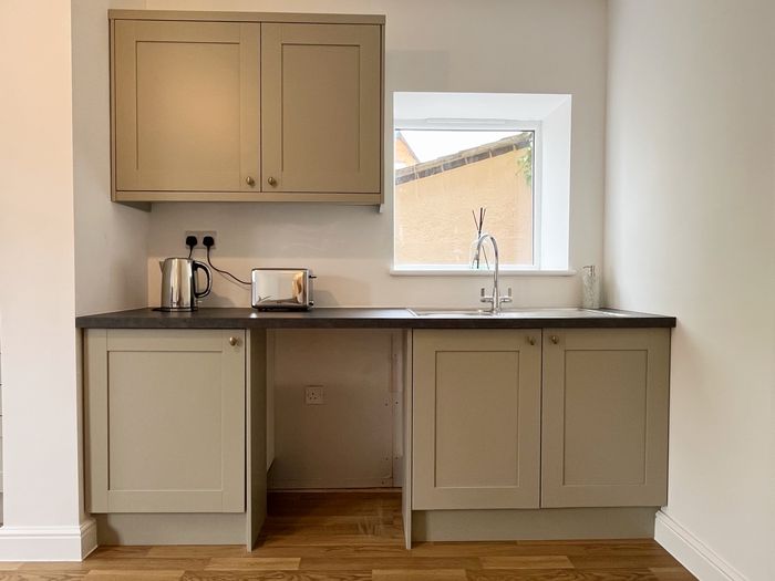 Kitchen run with sink, kettle and toaster below a window