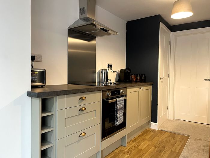 Kitchen with oven, induction hob, extractor and stainless steel splashback