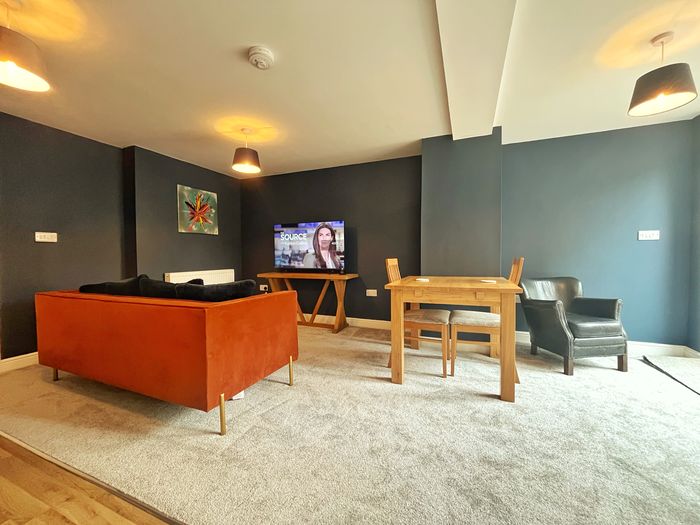 Burnt orange sofa facing the television, with a dining table and chairs alongside