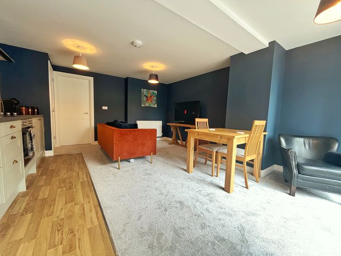 Open-plan kitchen, dining table and living area with deep blue walls