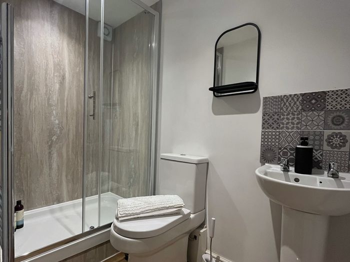 Shower room with a sliding glass shower enclosure, basin and patterned tiles
