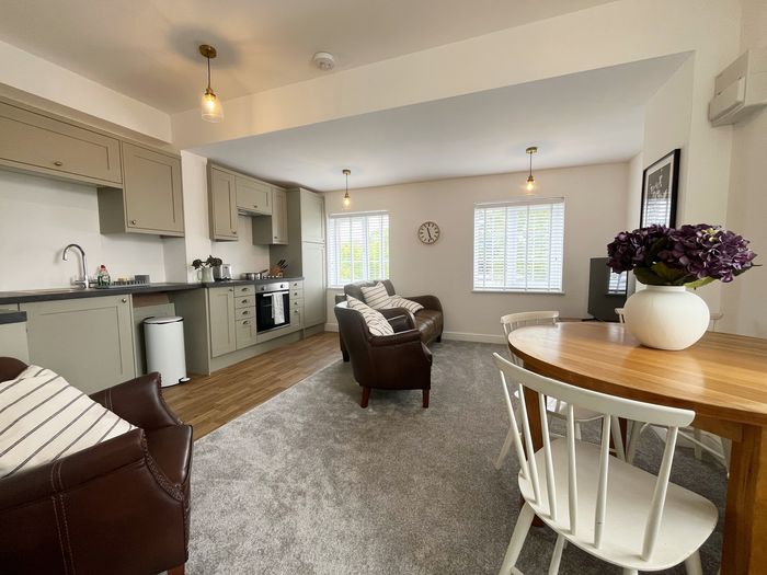 Open-plan living area with leather armchairs, dining table and kitchen beyond
