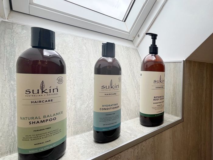 Sukin shampoo, conditioner and body wash on a tiled shower shelf